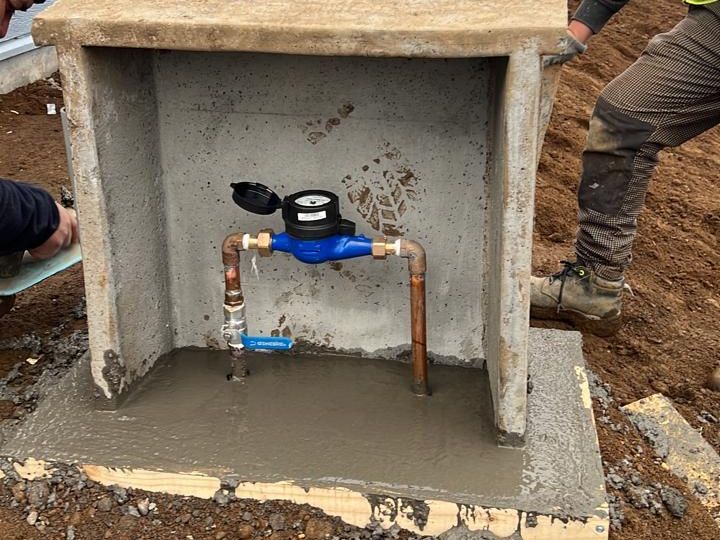 Cuadrilla instalando un nicho de medidor frente a una vivienda
