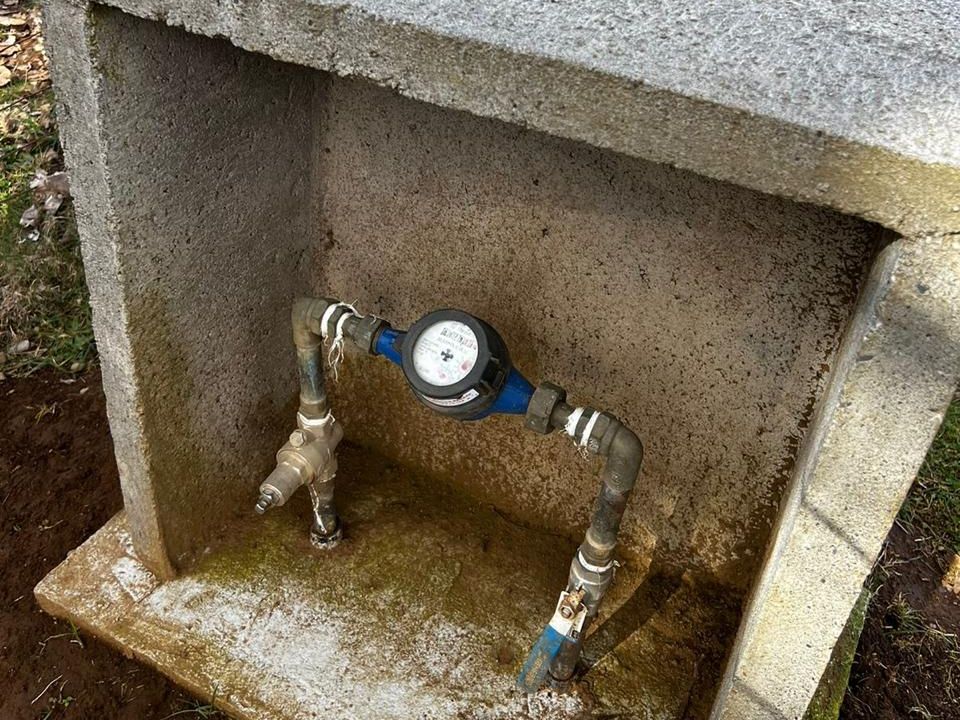 Medidor de agua potable instalado en nicho de hormigón con llaves de paso