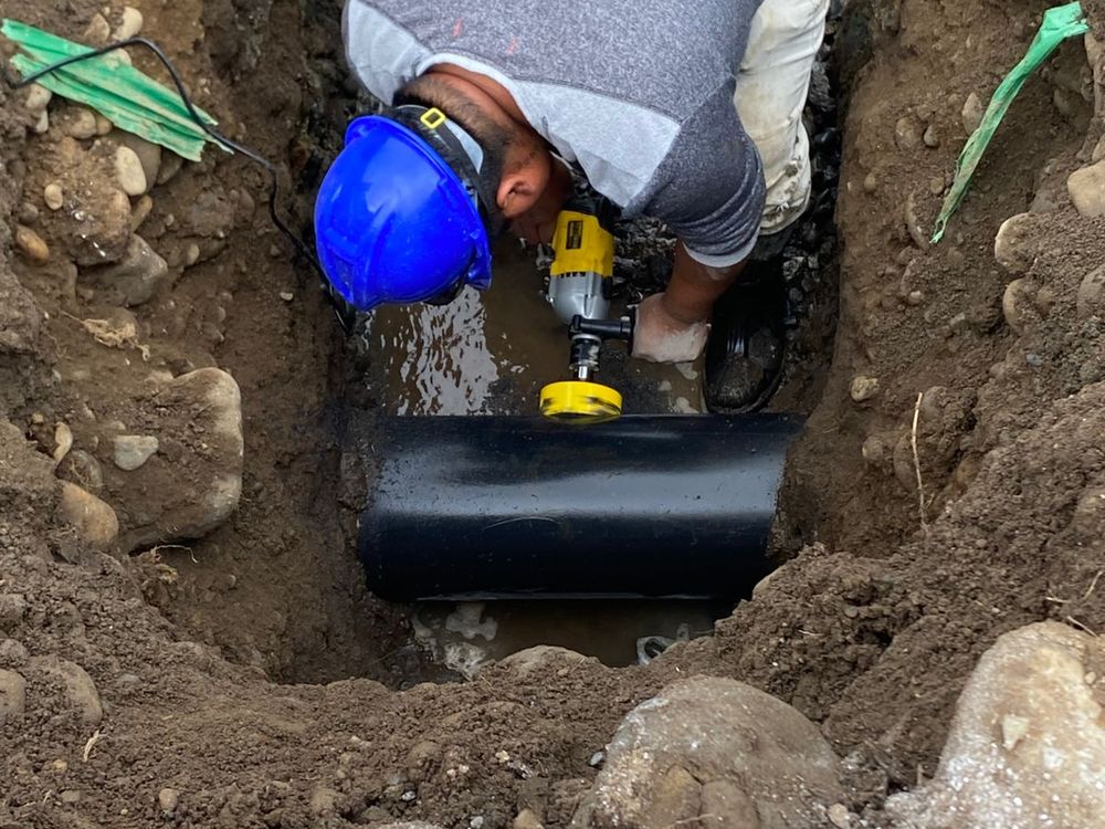Trabajador ejecutando la unión domiciliaria de alcantarillado sobre el colector