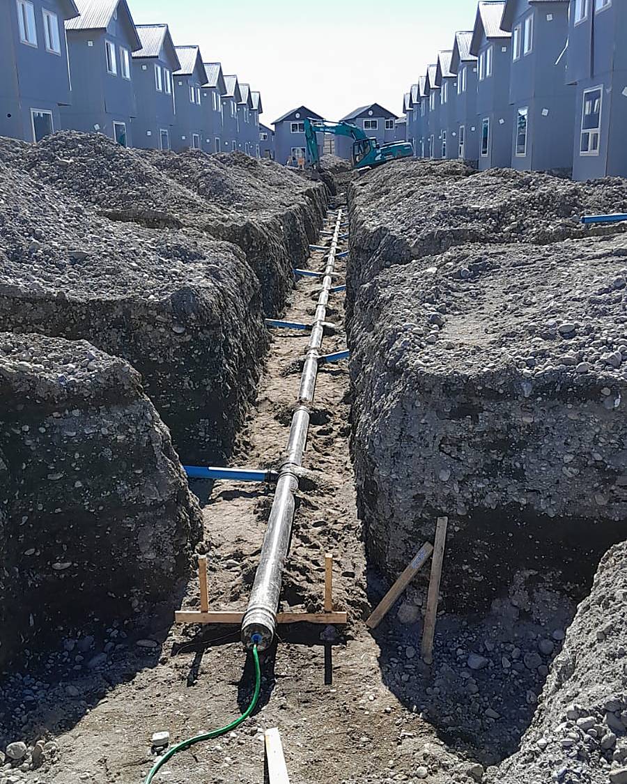 Colector de aguas servidas instalado en zanja entre viviendas de un proyecto de urbanización